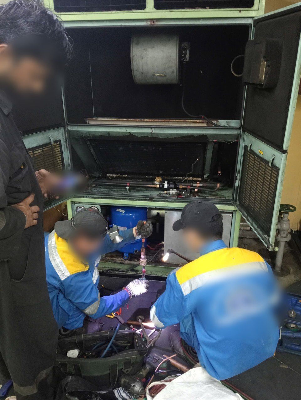 Technicians brazing the pipe connections of the new compressor during installation