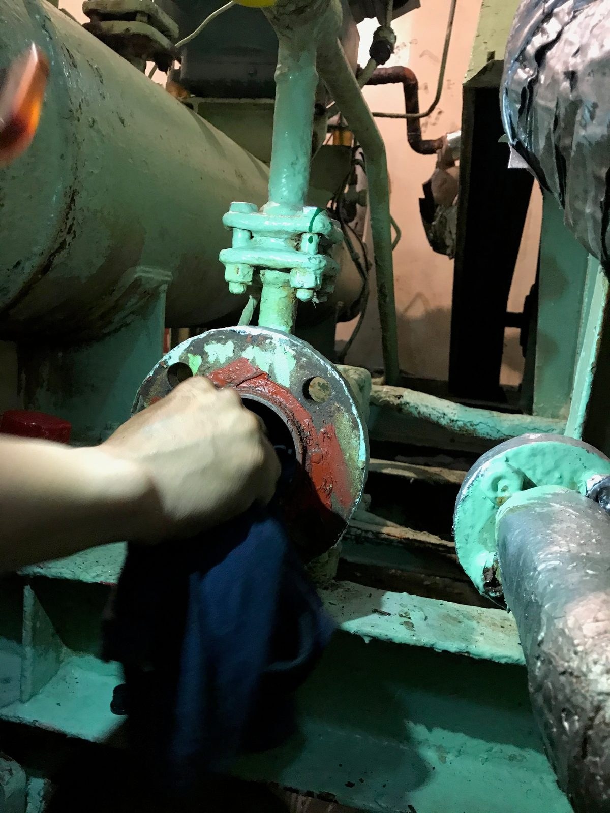 Technician working at an open pipe flange aboard a vessel