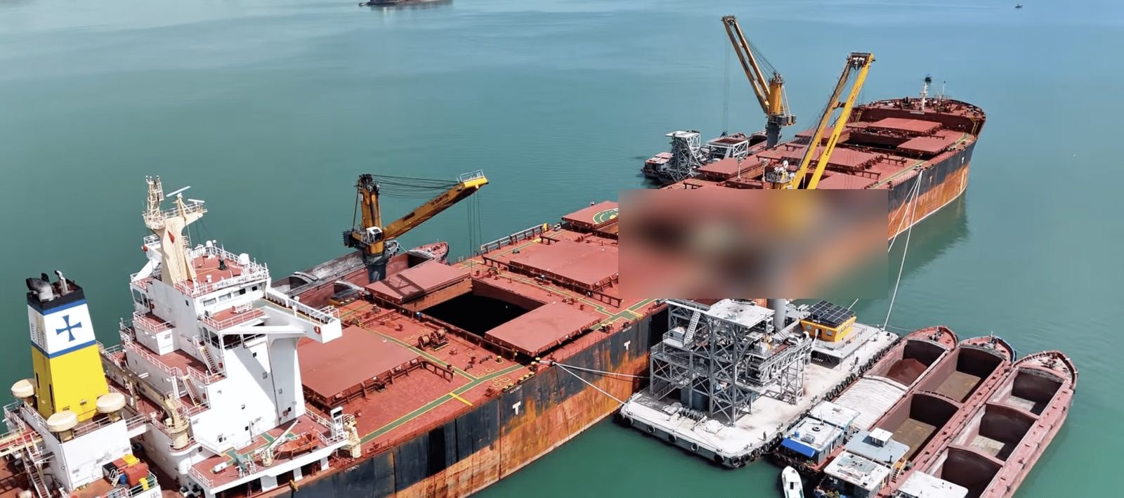 Floating crane discharging a bulk carrier into barges at anchorage