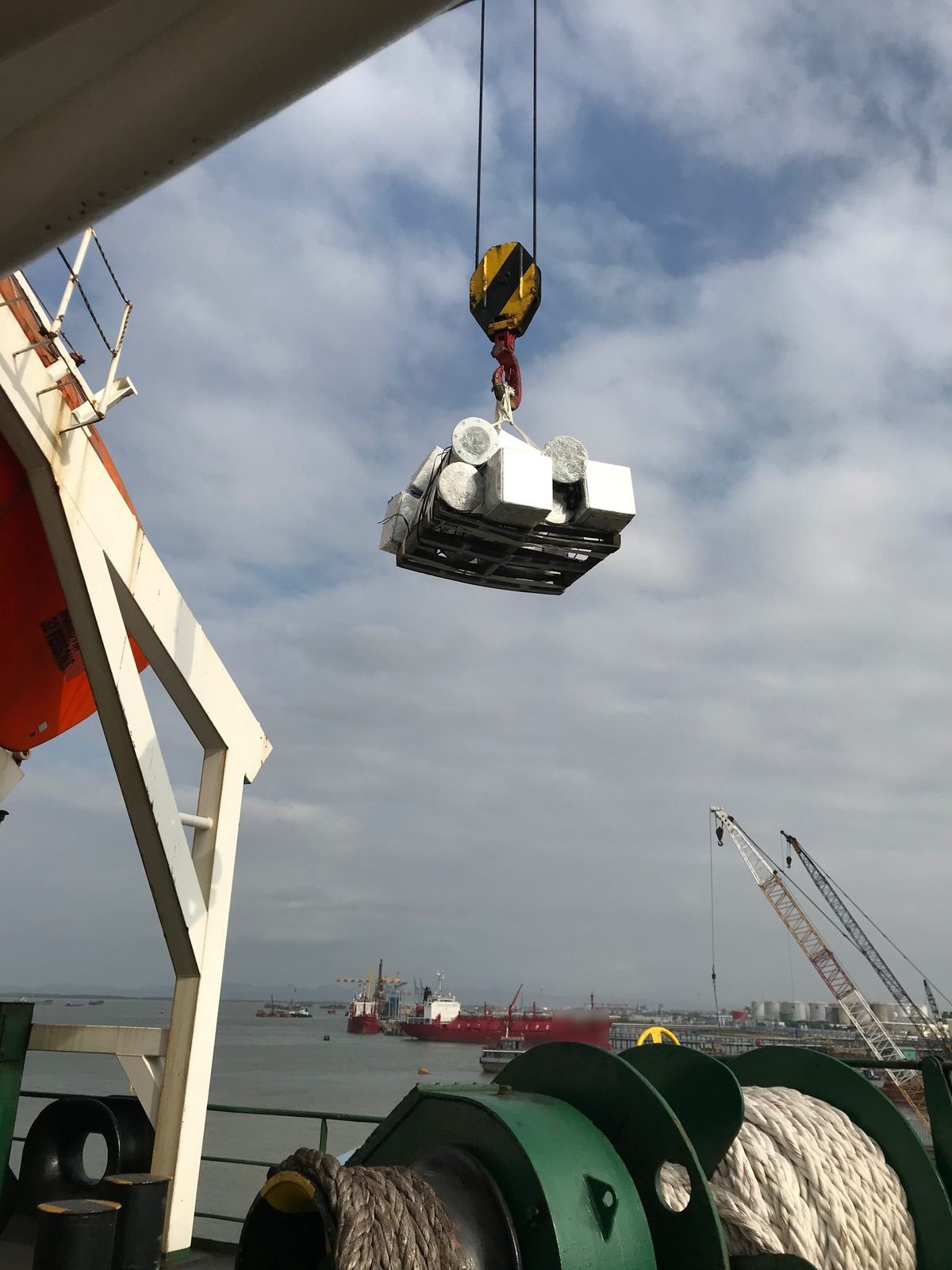 Pallet of wrapped metal components lifted alongside a vessel