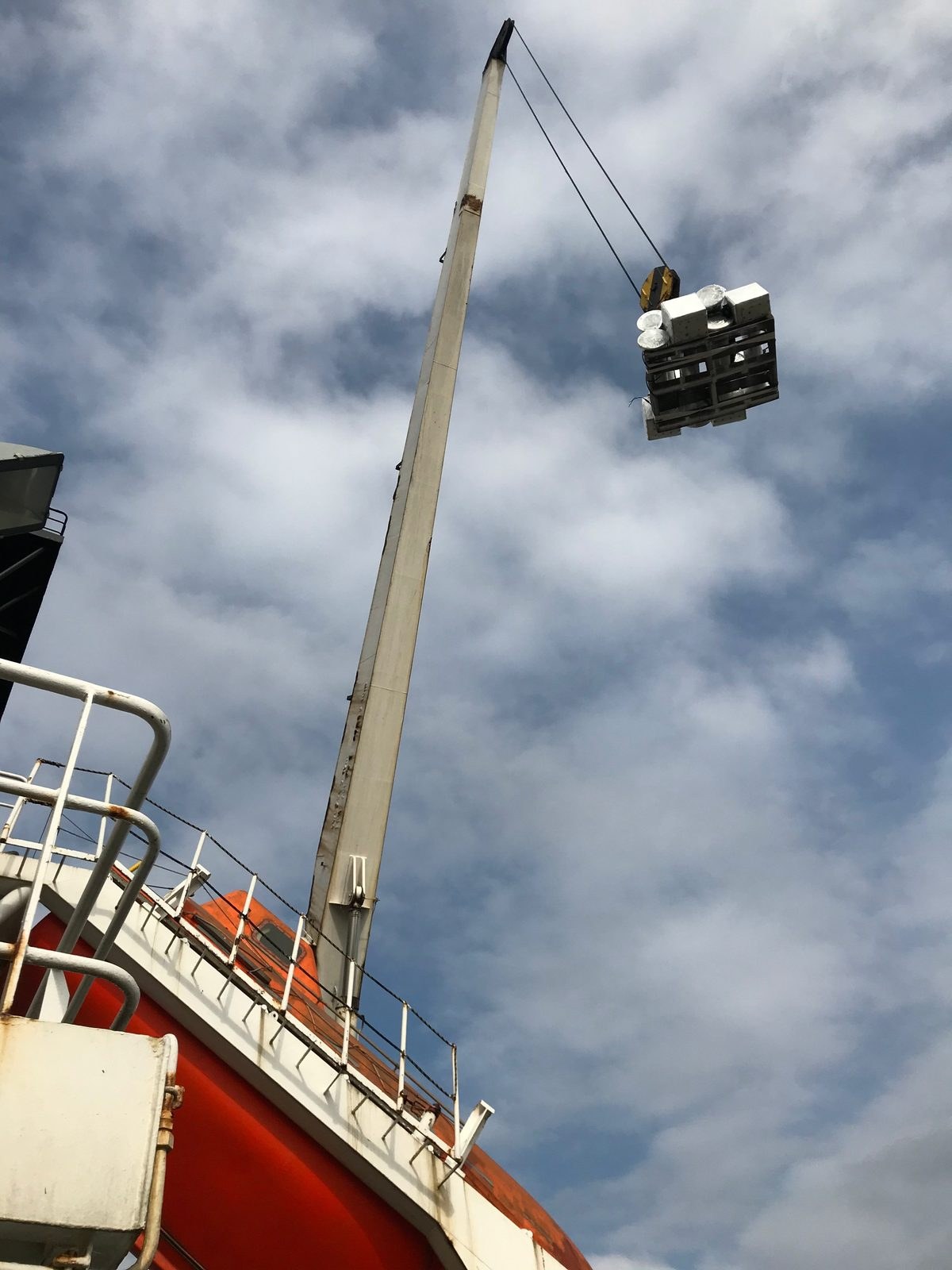 Vessel crane hoisting a pallet of wrapped metal components