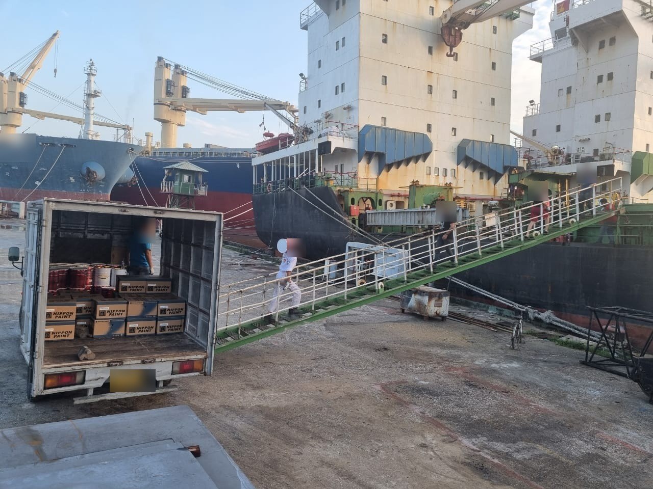 Marine paint stores unloaded from the truck and carried up the gangway.