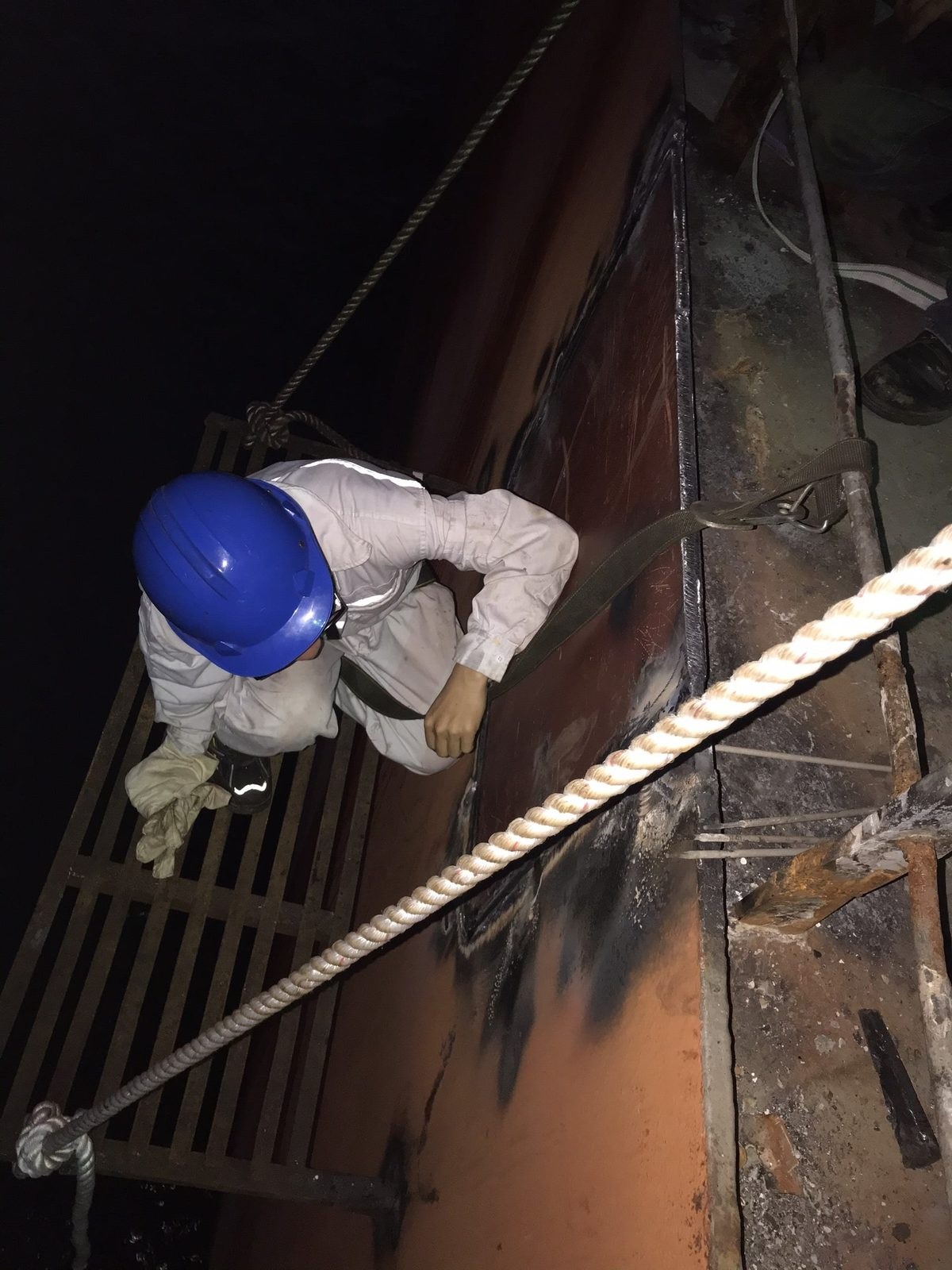 Repair work on the ship side from a stage at night