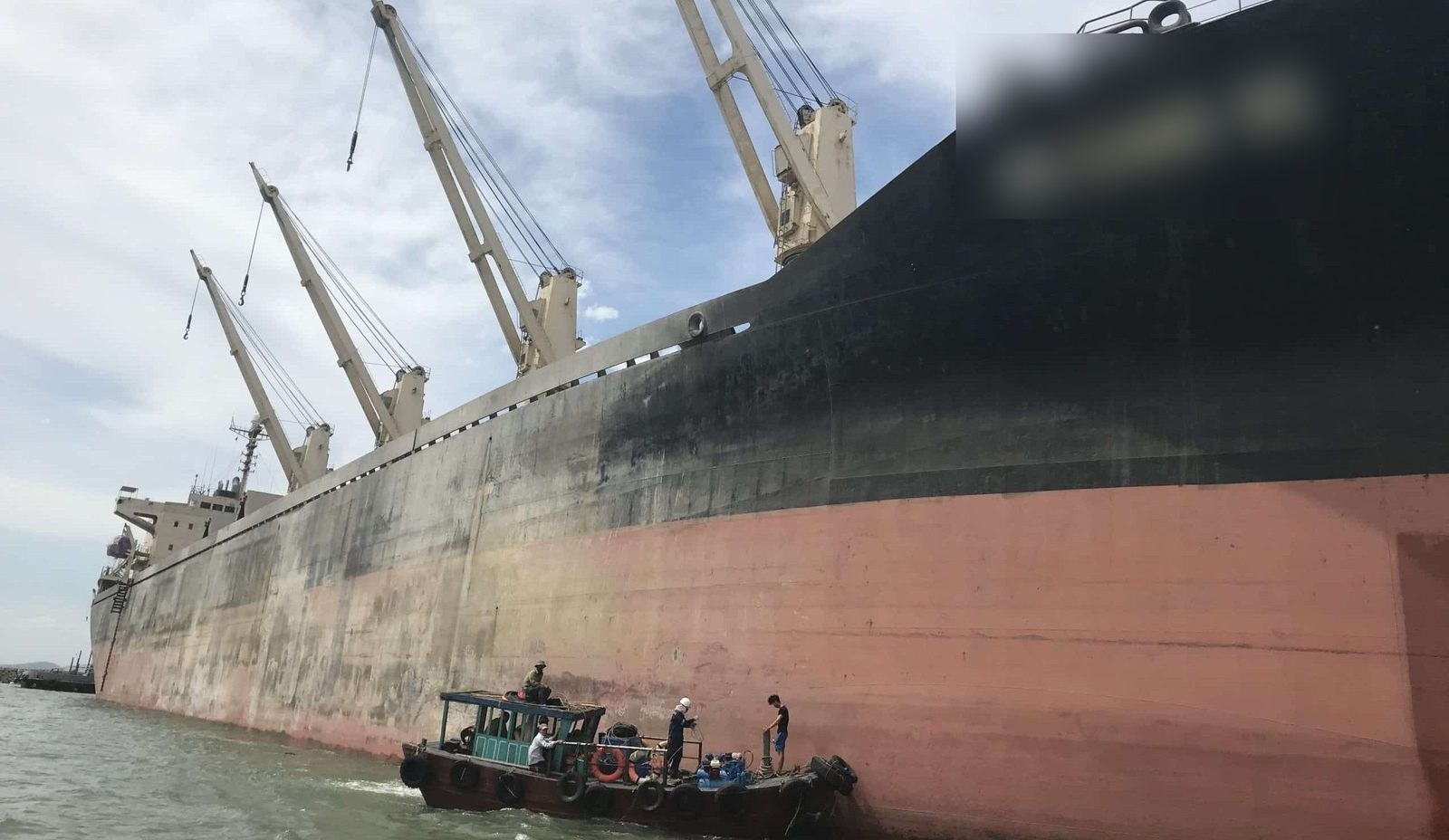 Diving support boat alongside a bulk carrier for underwater cleaning and CCTV inspection