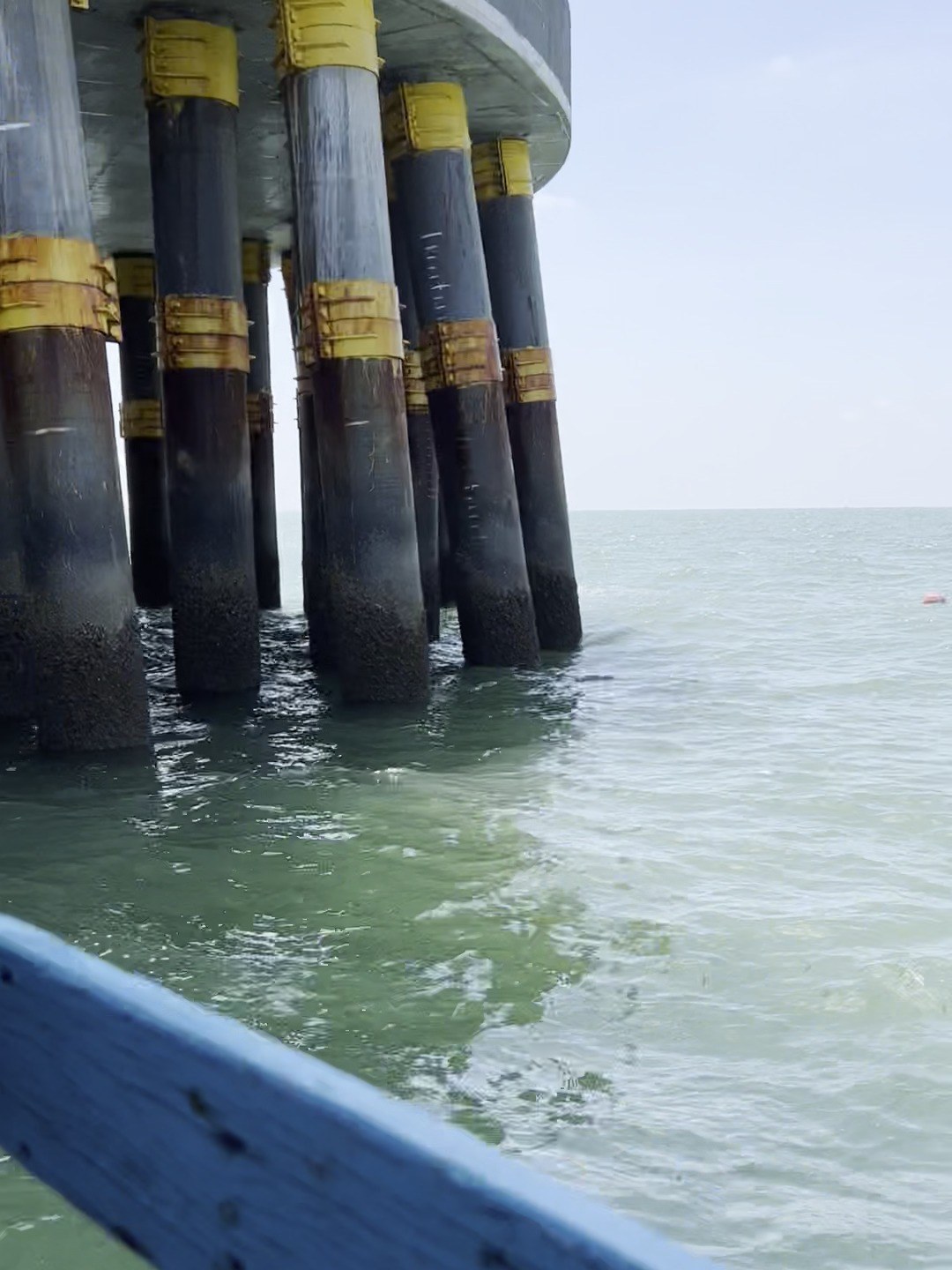Wind turbine foundation piles seen from a work boat, with a marker buoy beyond