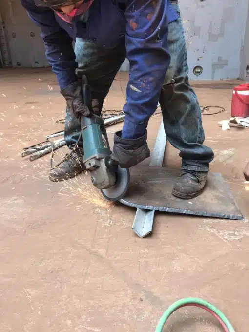 Replacement steel plate being prepared by grinding for vessel bulkhead repair